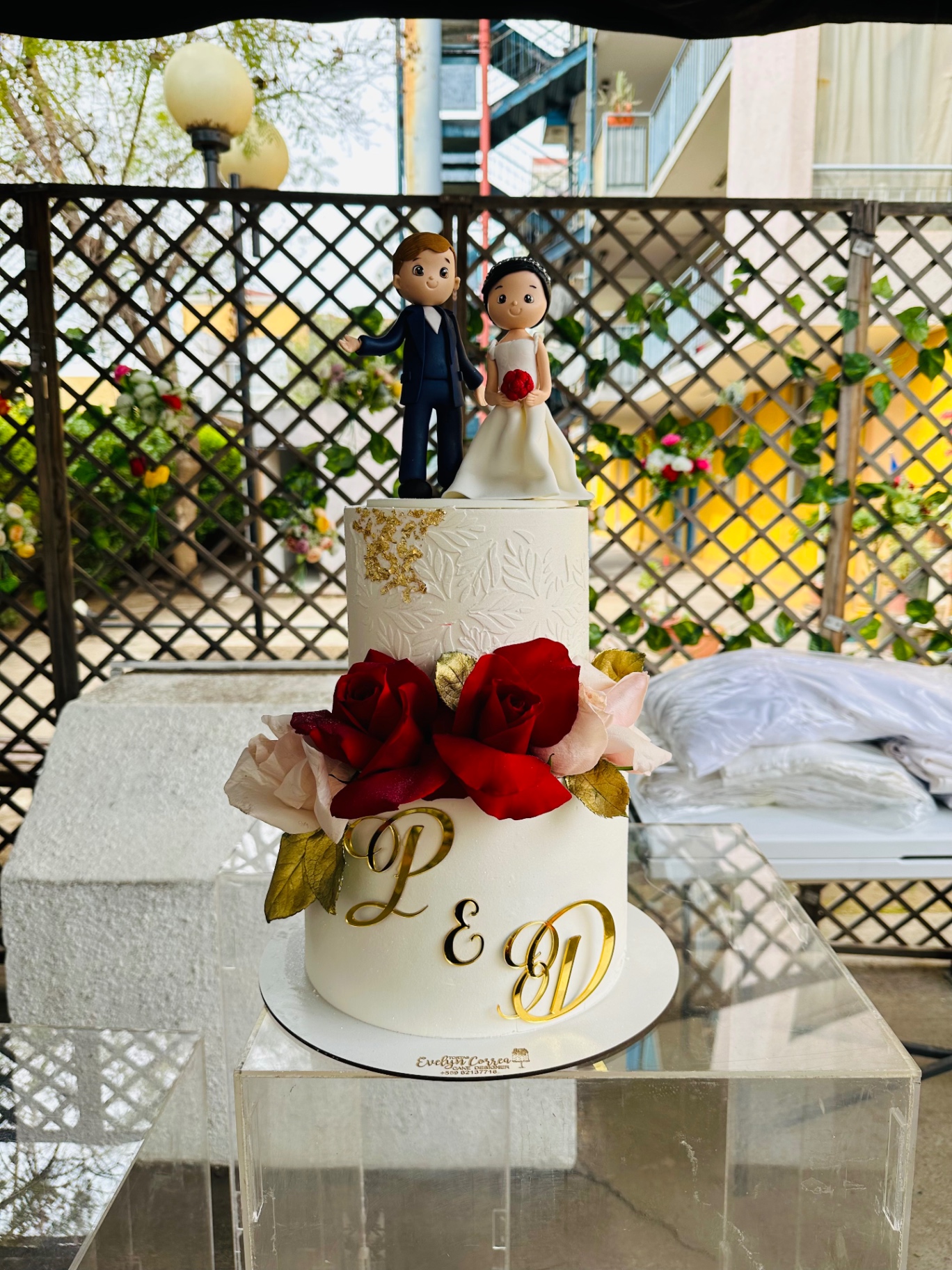 Torta de matrimonio blanca con rosas rojas y detalles dorados